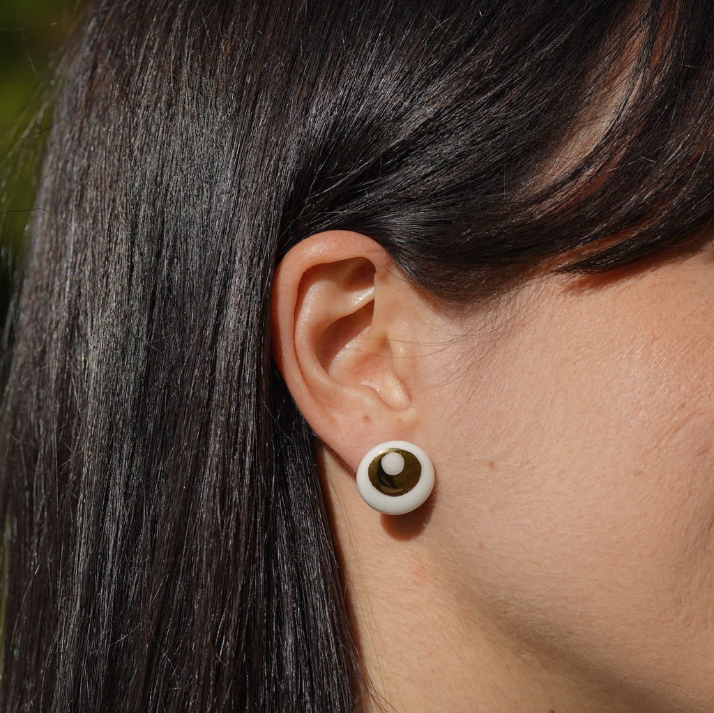 puces d’oreilles halo en porcelaine blanche et or potées à l'oreille