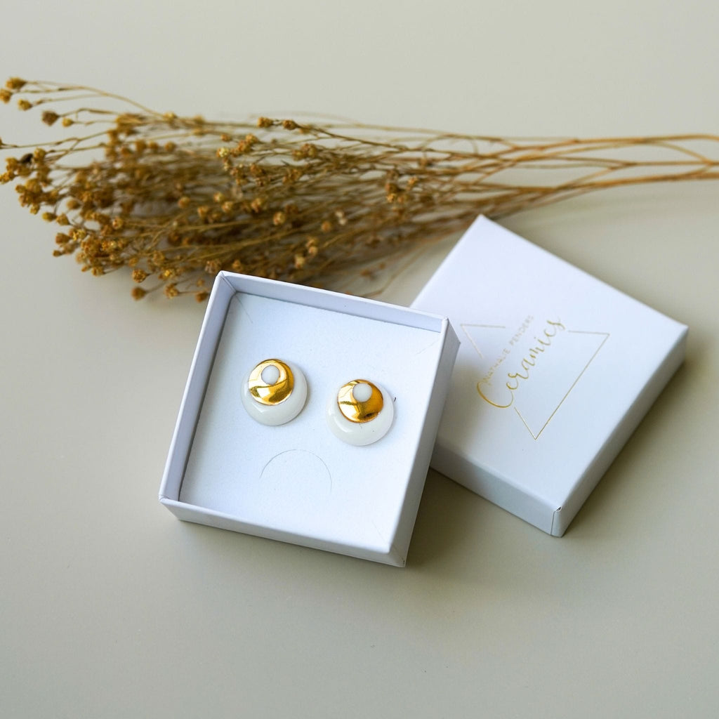 puces d’oreilles halo en porcelaine blanche et or dans leur écrin